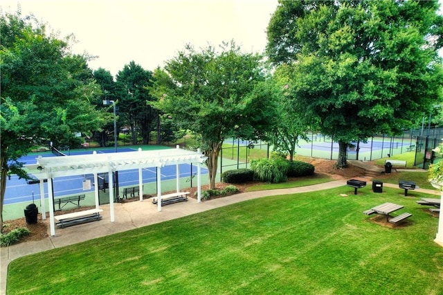 view of community featuring a yard, a pergola, and tennis court