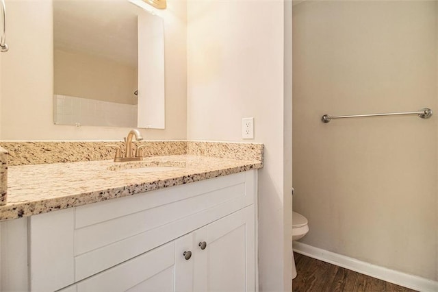 bathroom with wood-type flooring, vanity, and toilet