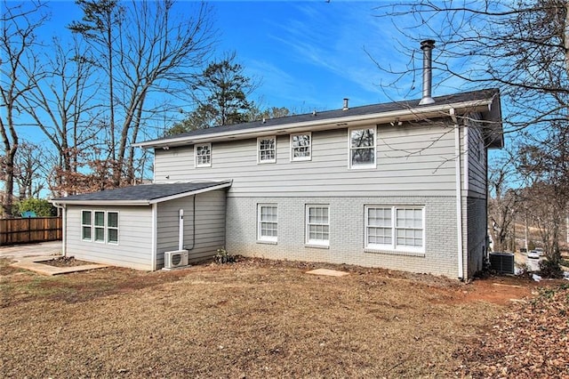 rear view of house featuring a lawn and central AC unit