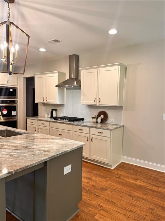 101 Red Oak Ln, Carrollton, GA 30116 - kitchen with wall chimney exhaust hood, stainless steel appliances, white cabinets, a chandelier, and light stone countertops