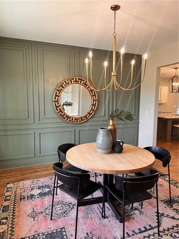 101 Red Oak Ln, Carrollton, GA 30116 - dining space featuring a chandelier, a decorative wall, and wood finished floors