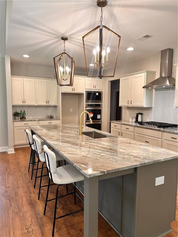 101 Red Oak Ln, Carrollton, GA 30116 - kitchen with wall chimney exhaust hood, stainless steel appliances, a chandelier, white cabinets, and recessed lighting