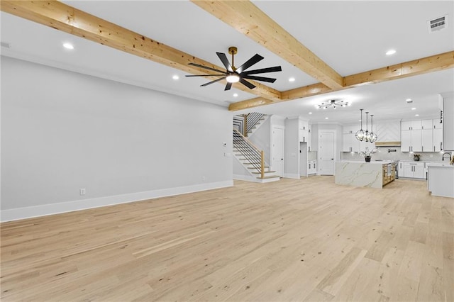 unfurnished living room with beamed ceiling, ceiling fan with notable chandelier, and light wood-type flooring