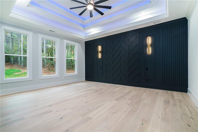 interior space with crown molding, a tray ceiling, ceiling fan, and light wood-type flooring