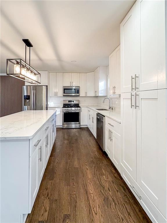 kitchen with sink, decorative light fixtures, stainless steel appliances, and white cabinets