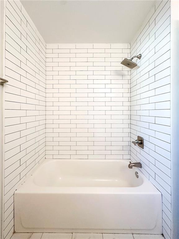 bathroom with tiled shower / bath combo and tile patterned floors