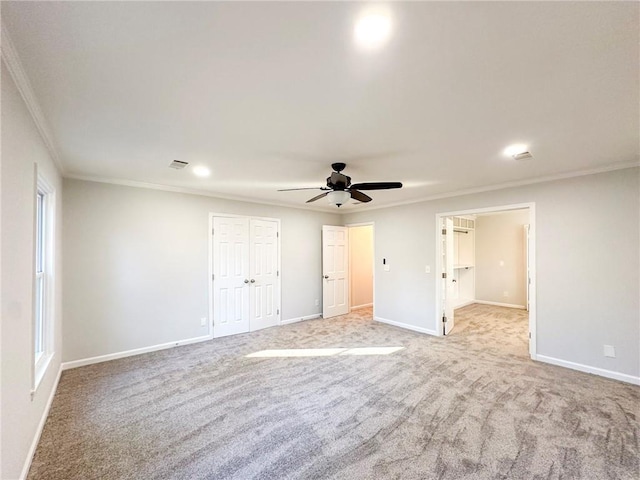 unfurnished bedroom featuring light carpet, ornamental molding, a closet, and ceiling fan