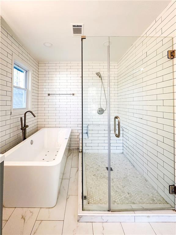 bathroom featuring plus walk in shower and tile walls