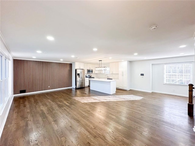 unfurnished living room featuring hardwood / wood-style flooring and ornamental molding