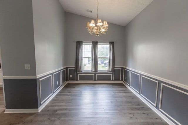 706 Hillmont Dr, Loganville, GA 30052 - unfurnished room with a chandelier, vaulted ceiling, wainscoting, wood finished floors, and a decorative wall
