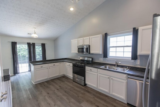 706 Hillmont Dr, Loganville, GA 30052 - kitchen with stainless steel appliances, a textured ceiling, a peninsula, dark countertops, and white cabinetry