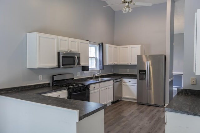 706 Hillmont Dr, Loganville, GA 30052 - kitchen with appliances with stainless steel finishes, high vaulted ceiling, dark countertops, a peninsula, and white cabinets