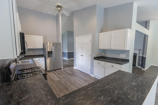 706 Hillmont Dr, Loganville, GA 30052 - kitchen featuring stainless steel fridge with ice dispenser, a ceiling fan, dark stone counters, wood finished floors, and high vaulted ceiling