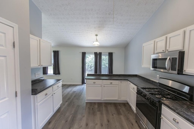 706 Hillmont Dr, Loganville, GA 30052 - kitchen featuring stainless steel microwave, gas range, a textured ceiling, dark countertops, and a peninsula