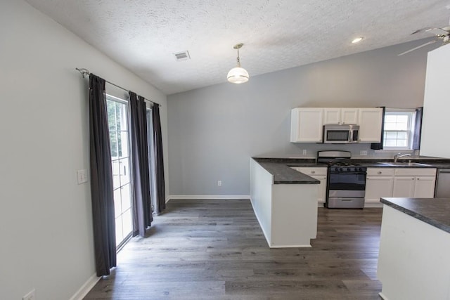 706 Hillmont Dr, Loganville, GA 30052 - kitchen with stainless steel appliances, dark countertops, a textured ceiling, white cabinetry, and dark wood finished floors