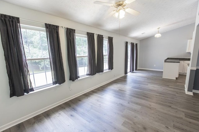 706 Hillmont Dr, Loganville, GA 30052 - unfurnished living room featuring a textured ceiling, lofted ceiling, plenty of natural light, dark wood-style floors, and a ceiling fan