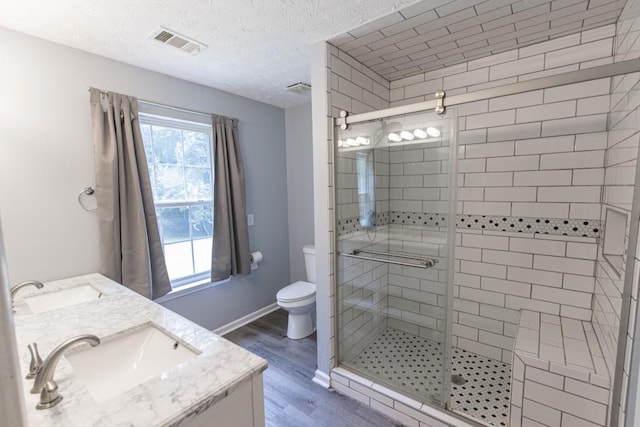 706 Hillmont Dr, Loganville, GA 30052 - full bathroom featuring wood finished floors, a stall shower, double vanity, and a textured ceiling