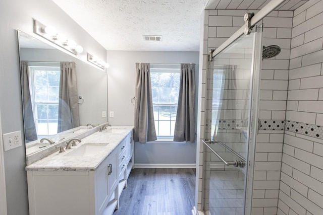 706 Hillmont Dr, Loganville, GA 30052 - bathroom with wood finished floors, double vanity, a shower stall, healthy amount of natural light, and a textured ceiling