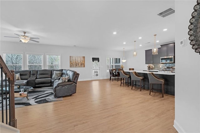 living room featuring ceiling fan, light hardwood / wood-style floors, and sink