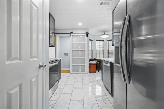 kitchen featuring visible vents, marble finish floor, stainless steel appliances, a barn door, and light countertops