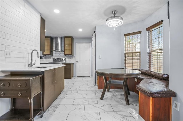 kitchen with backsplash, stainless steel electric range oven, marble finish floor, wall chimney exhaust hood, and a sink