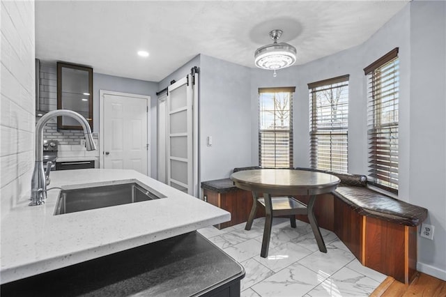 kitchen featuring marble finish floor, a sink, recessed lighting, a barn door, and baseboards