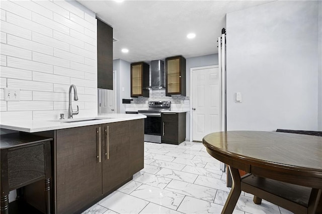 kitchen with marble finish floor, stainless steel range with electric stovetop, a sink, wall chimney exhaust hood, and light countertops