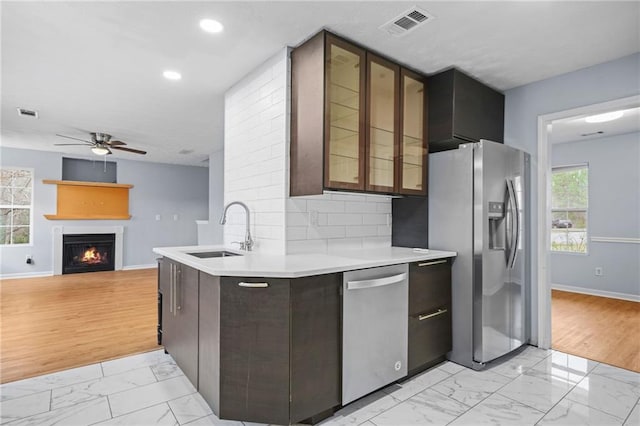 kitchen featuring marble finish floor, a ceiling fan, a sink, stainless steel appliances, and light countertops