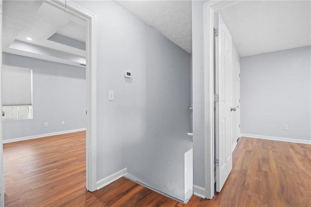 hallway featuring an upstairs landing, baseboards, and wood finished floors