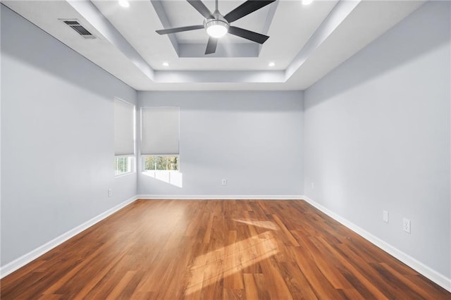 unfurnished room with visible vents, wood finished floors, recessed lighting, baseboards, and a raised ceiling