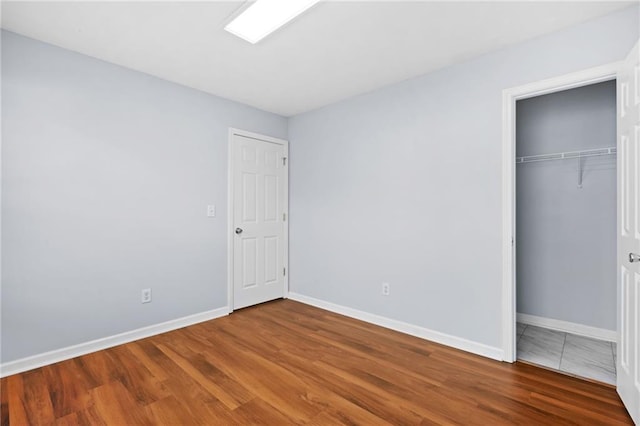 unfurnished bedroom with a closet, baseboards, and wood finished floors