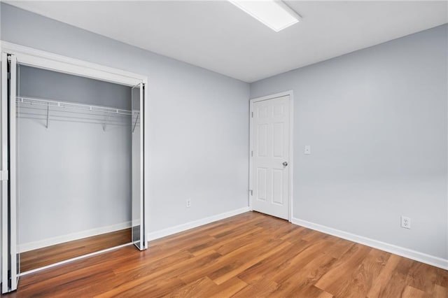 unfurnished bedroom with a closet, baseboards, and wood finished floors