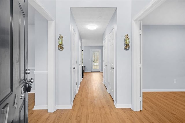 hallway with light wood-type flooring and baseboards