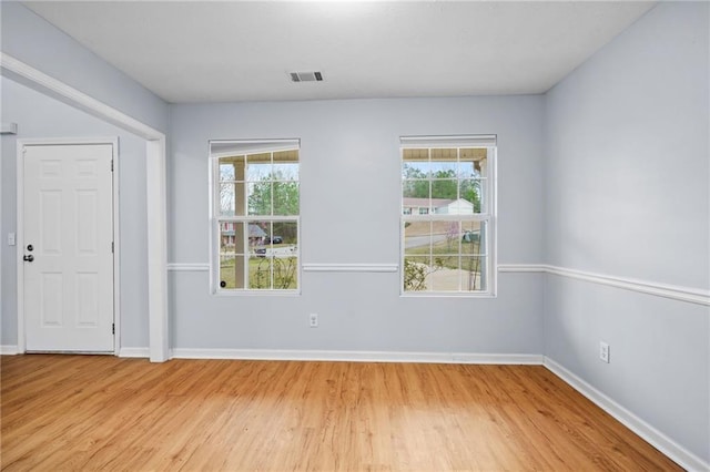 unfurnished room featuring a wealth of natural light, visible vents, and light wood-style flooring