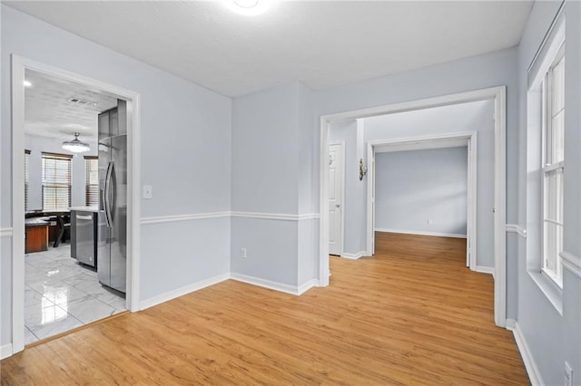 unfurnished room featuring light wood finished floors and baseboards