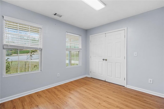 unfurnished bedroom with light wood-style flooring, baseboards, visible vents, and a closet