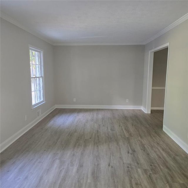 empty room featuring crown molding, baseboards, and wood finished floors