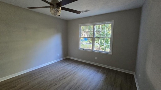 unfurnished room featuring visible vents, dark wood finished floors, baseboards, and ceiling fan