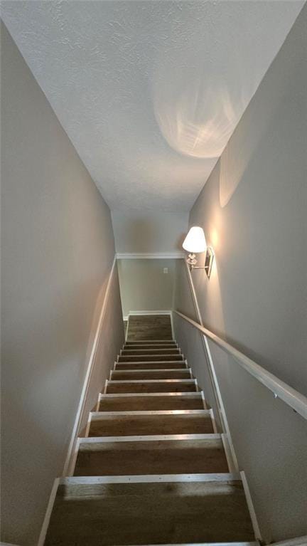 stairway with baseboards and a textured ceiling