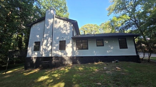 back of house featuring a lawn and a chimney