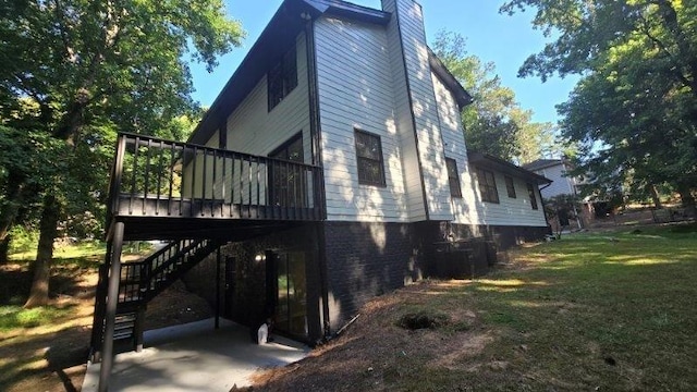 view of property exterior featuring stairs, a deck, a chimney, and a lawn