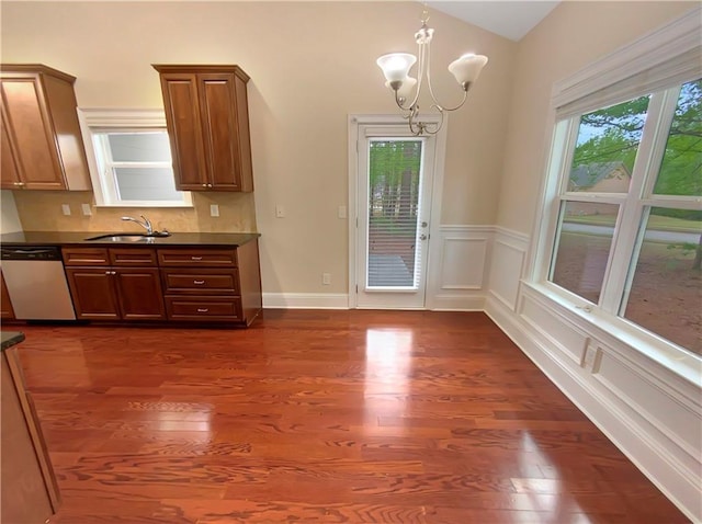 kitchen with dark hardwood / wood-style flooring, decorative backsplash, sink, an inviting chandelier, and stainless steel dishwasher