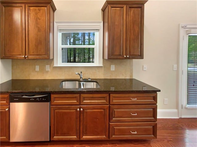 kitchen featuring sink, dark stone countertops, dishwasher, and dark wood-type flooring