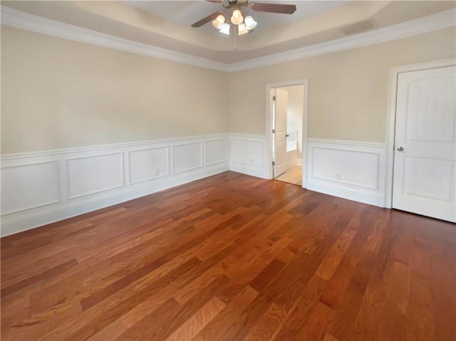 unfurnished room featuring ceiling fan, a tray ceiling, crown molding, and wood-type flooring