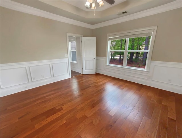 spare room featuring hardwood / wood-style flooring, ceiling fan, ornamental molding, and a tray ceiling