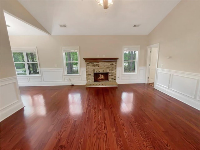 unfurnished living room with lofted ceiling, a brick fireplace, and dark hardwood / wood-style floors