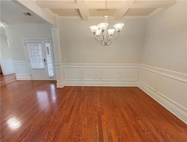 spare room featuring hardwood / wood-style floors, coffered ceiling, ornamental molding, beam ceiling, and an inviting chandelier