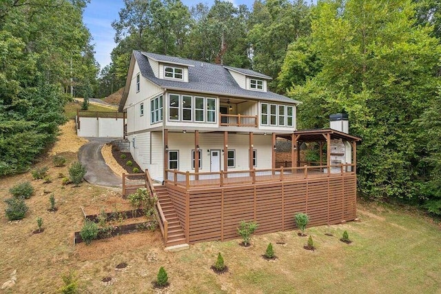 rear view of property featuring a gazebo, ceiling fan, a sunroom, and a deck