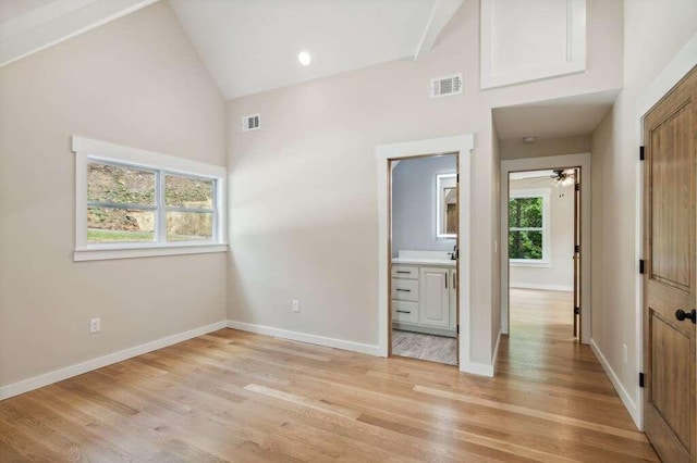 unfurnished bedroom with ensuite bath, high vaulted ceiling, and light hardwood / wood-style flooring