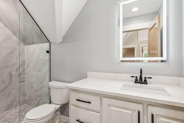 bathroom with vanity, toilet, and a tile shower